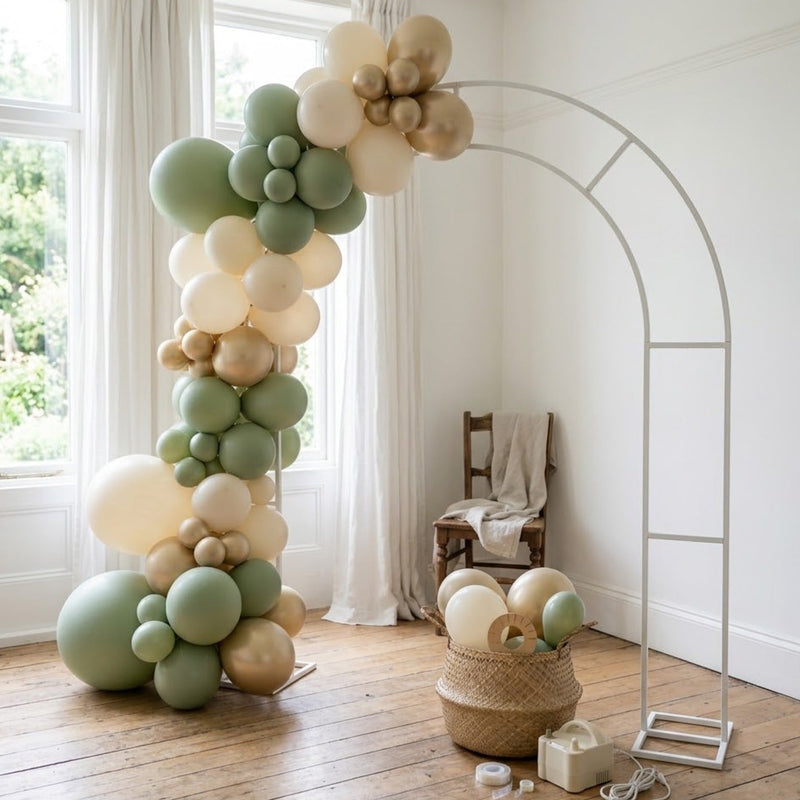 Arche de ballons sauge, ivoire et or en cours de montage sur sa structure blanche
