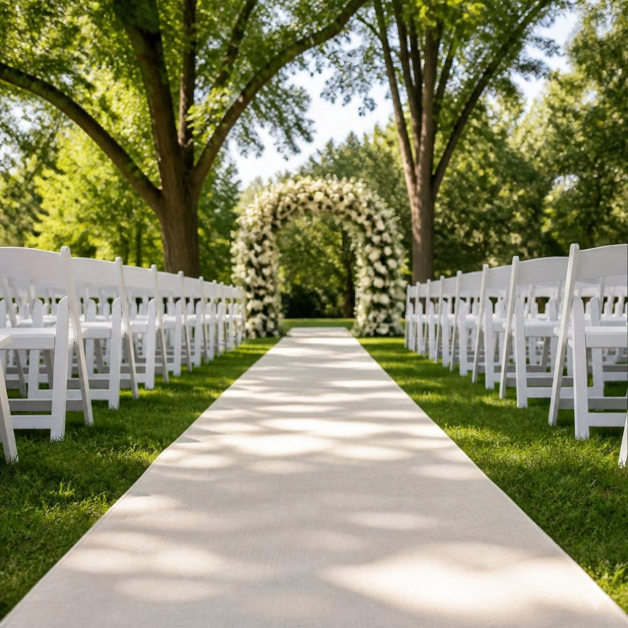 Long tapis d'allée ivoire sur une pelouse entre deux rangées de chaises blanches, menant à une arche fleurie